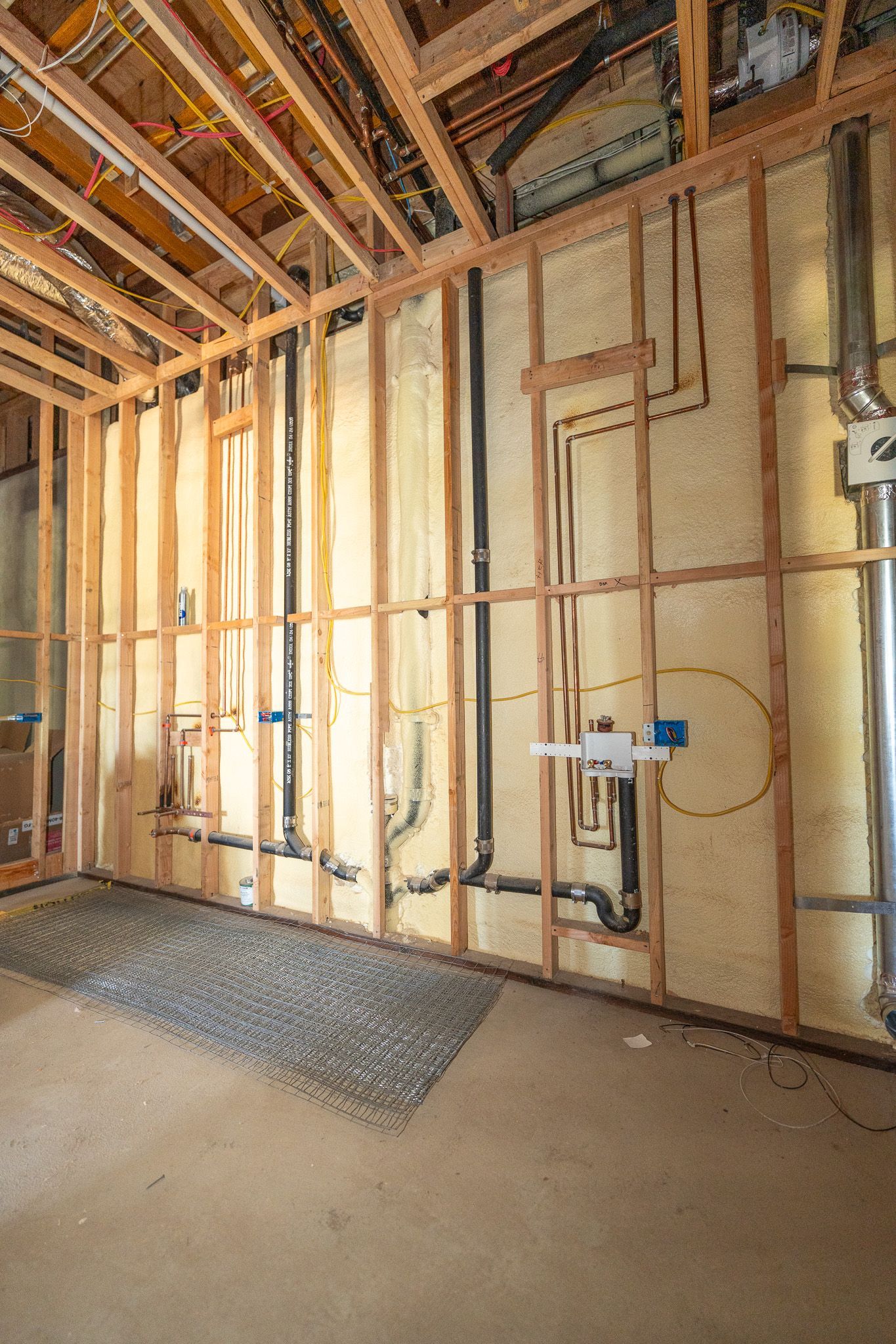 Worker installing yellow insulation in a wall cavity indoors
