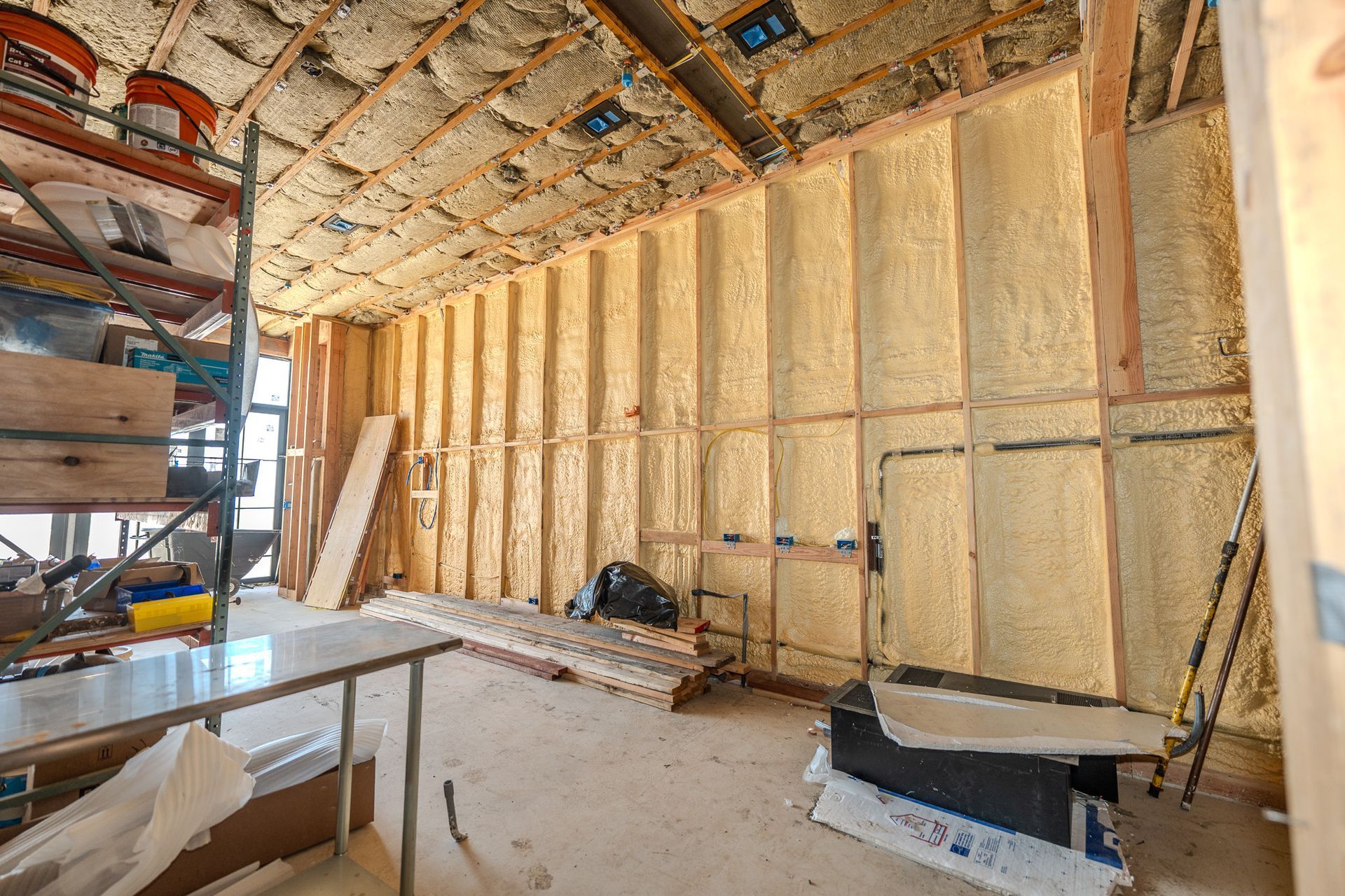 Hand measuring pink insulation batts between wooden studs with a ruler