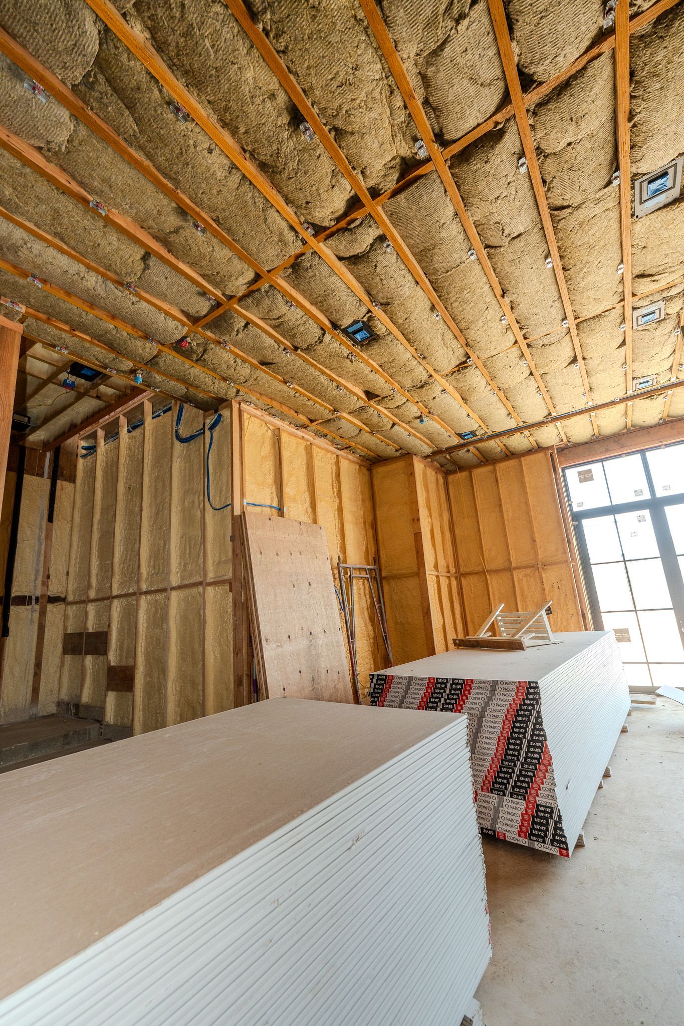 Exposed ceiling insulation and wooden beams in an unfinished attic or roof structure