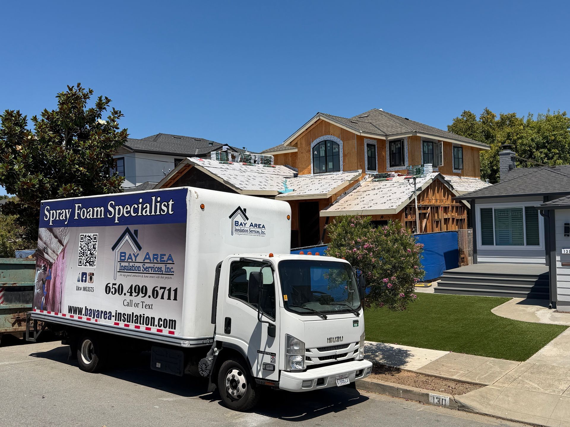 Moving truck parked in front of a suburban house during roof repair, with ladders and materials visible