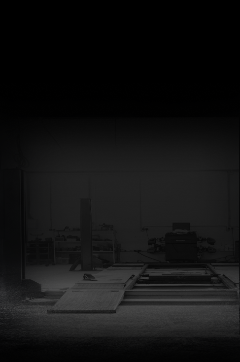 A dimly lit auto repair shop with a car lift and tools visible.
