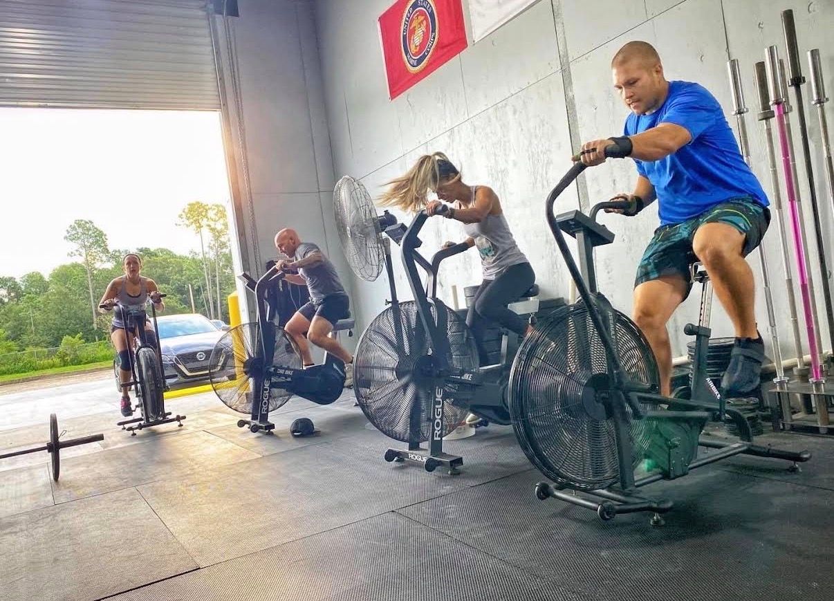 People exercising on rowing machines in CrossFit Fernandina in Yulee,FL, with one person standing nearby.