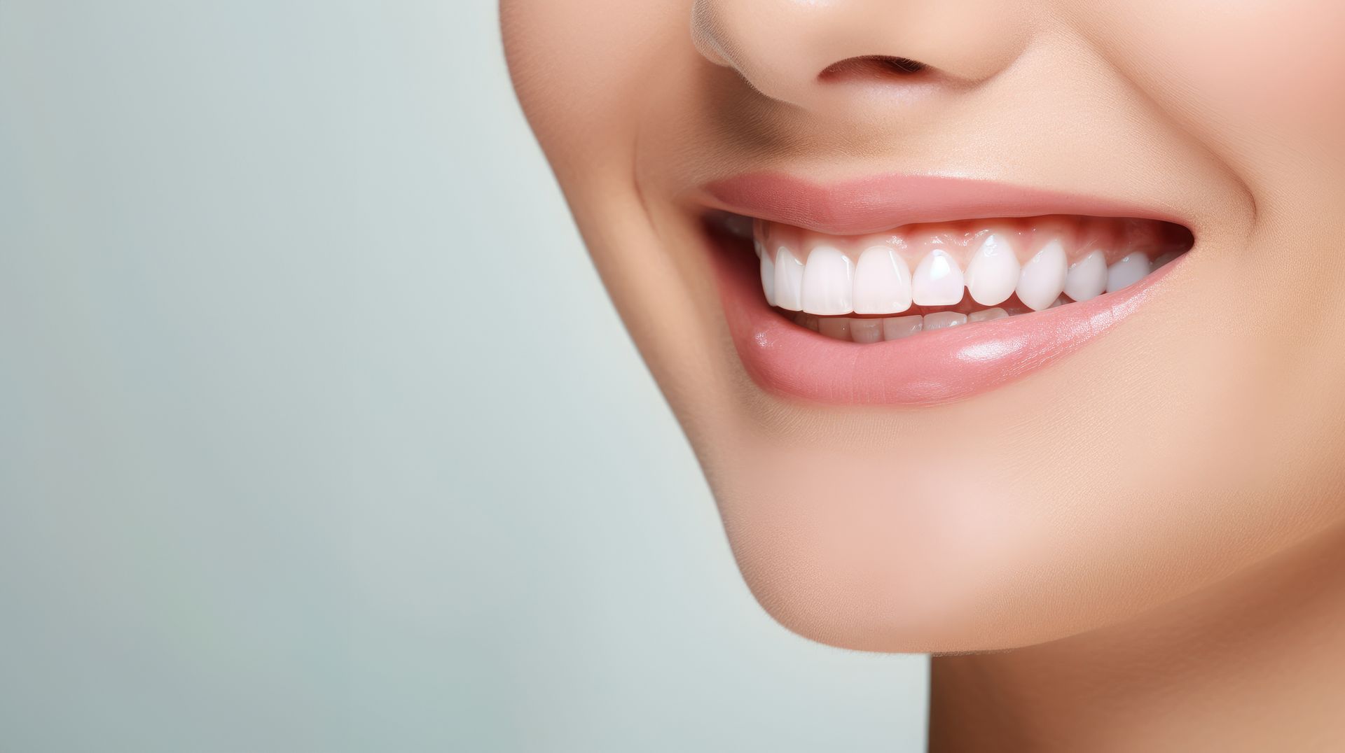 Close-up of a smiling mouth with white teeth and glossy pink lips