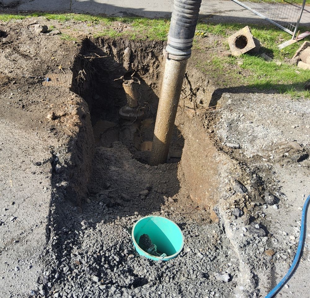 Trench Excavation Around a Vertical Pipe With a Green Drain Opening in Dirt — Fud's Concreting In Collinsville, QLD