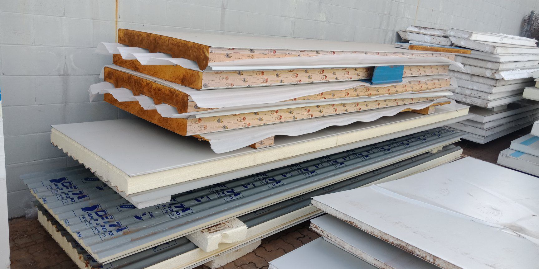 Stacked white foam and mattress slabs in a warehouse, with layered orange insulation exposed on top. — Arctic Installations in Winnellie, NT