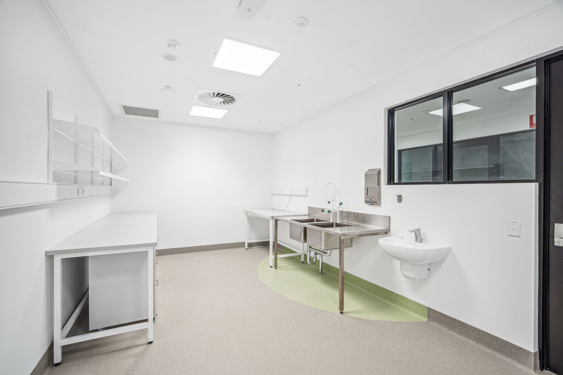 Bright clinical room with sink, counter, stainless table, and black-framed window. — Arctic Installations in Winnellie, NT
