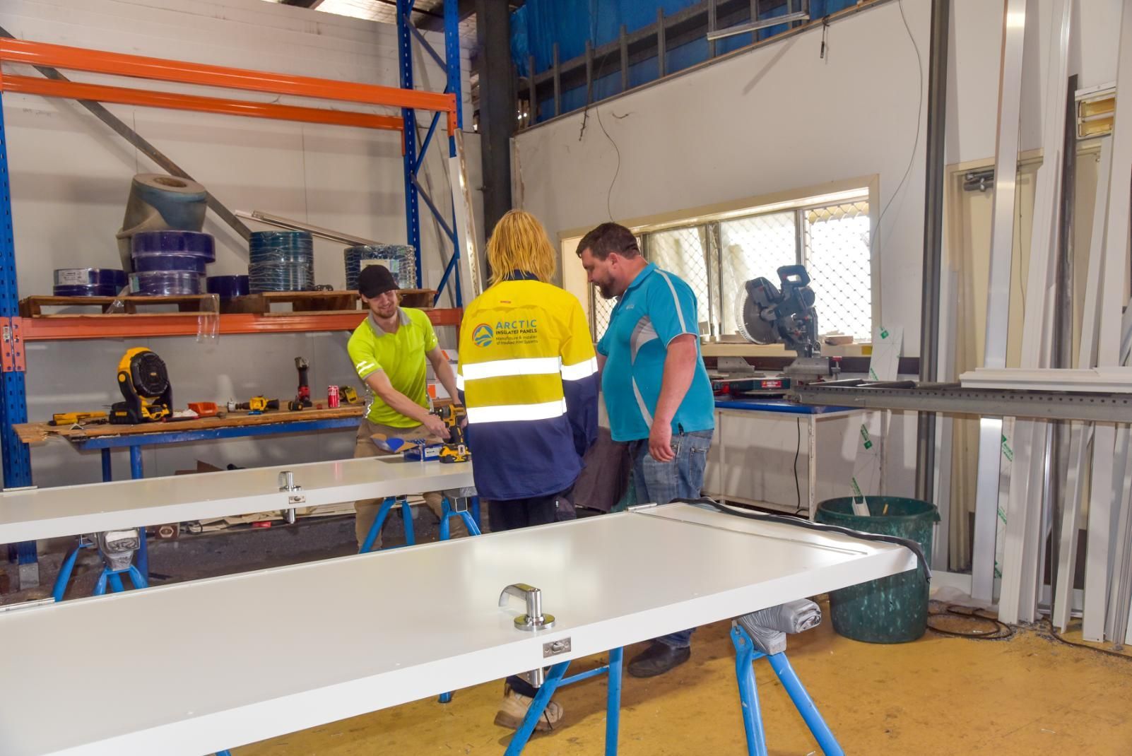 A Man Is Holding a Hard Hat in A Warehouse — Arctic Installations in Winnellie, NT