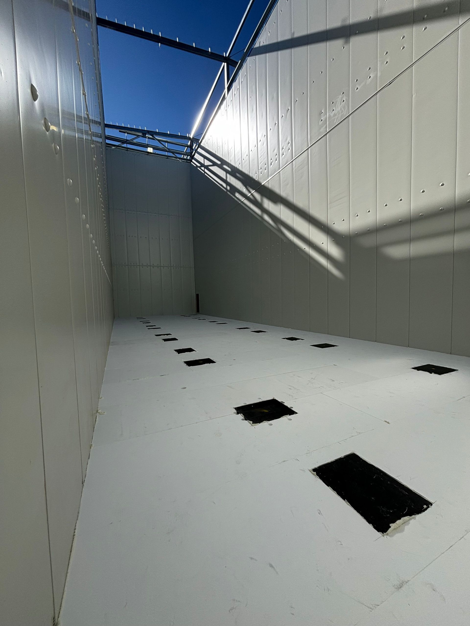 A Wide, White, Enclosed Space With a Line of Rectangular Black Patches — Arctic Installations in Winnellie, NT