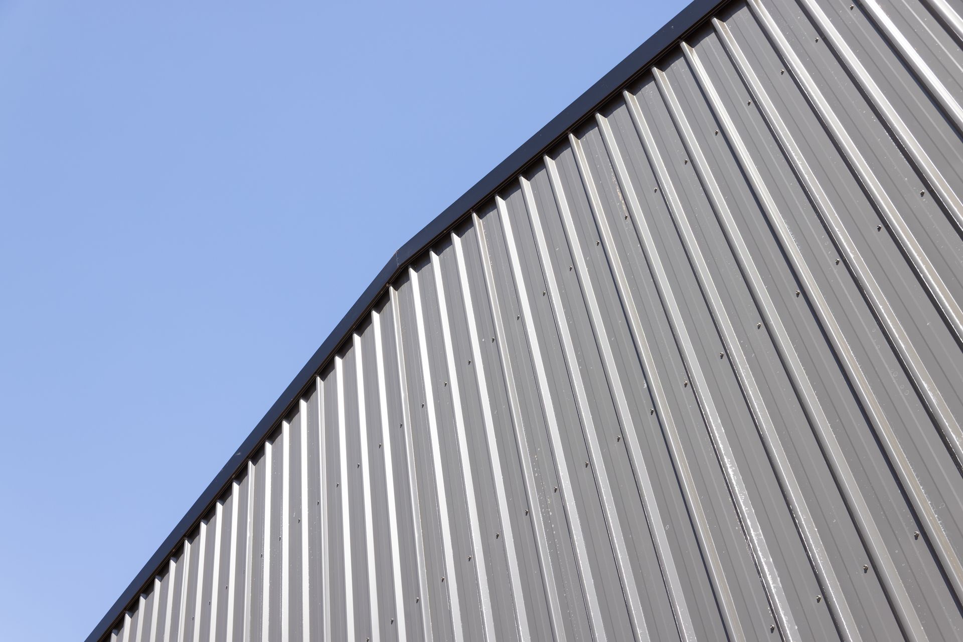Curved corrugated metal wall against a clear blue sky — Arctic Installations in Winnellie, NT