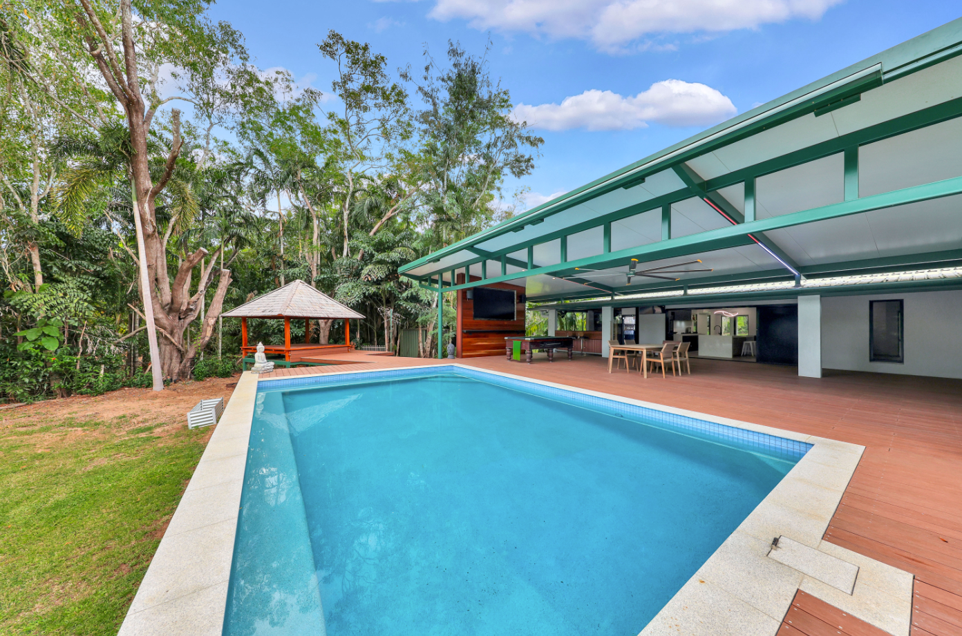 A large swimming pool is in the backyard of a house.