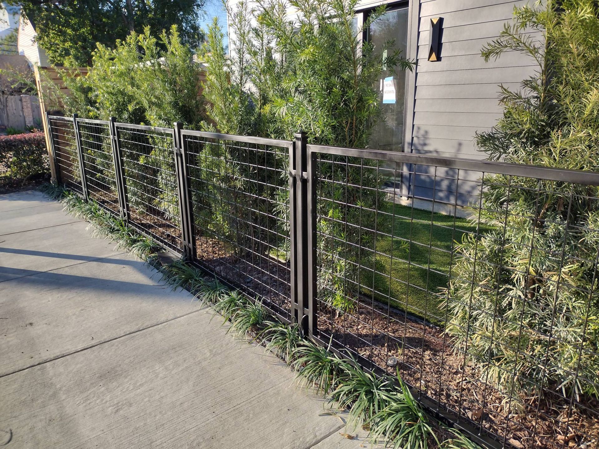 A Metal Fence Surrounds a Concrete Driveway in Front of A House - Houston, TX - Rio Grande Fence Company