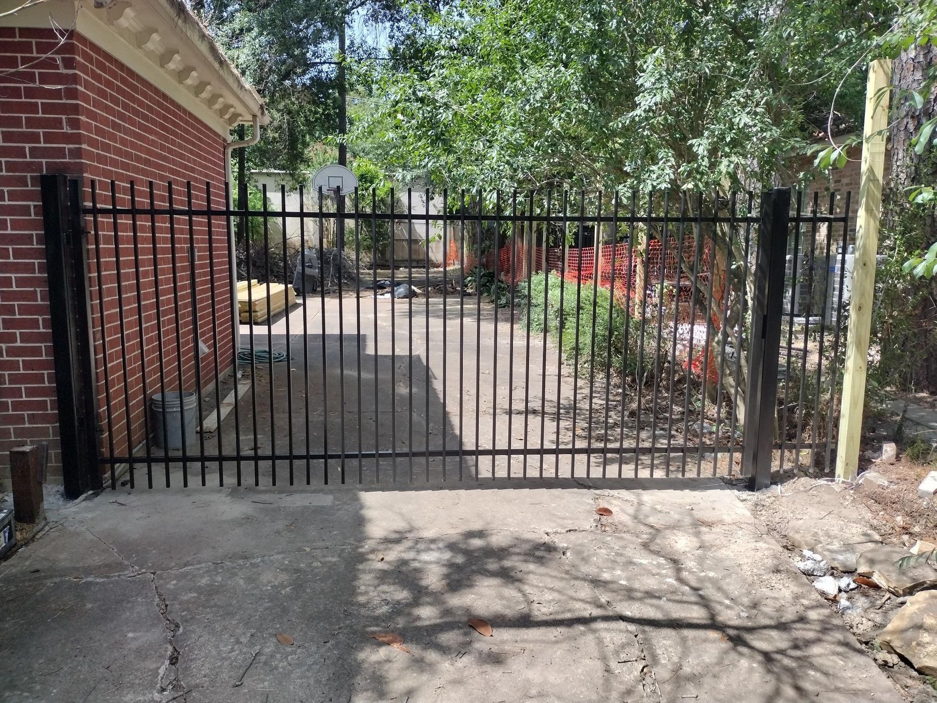 A Black Metal Gate Is Sitting in Front of A Brick Building - Houston, TX - Rio Grande Fence Company