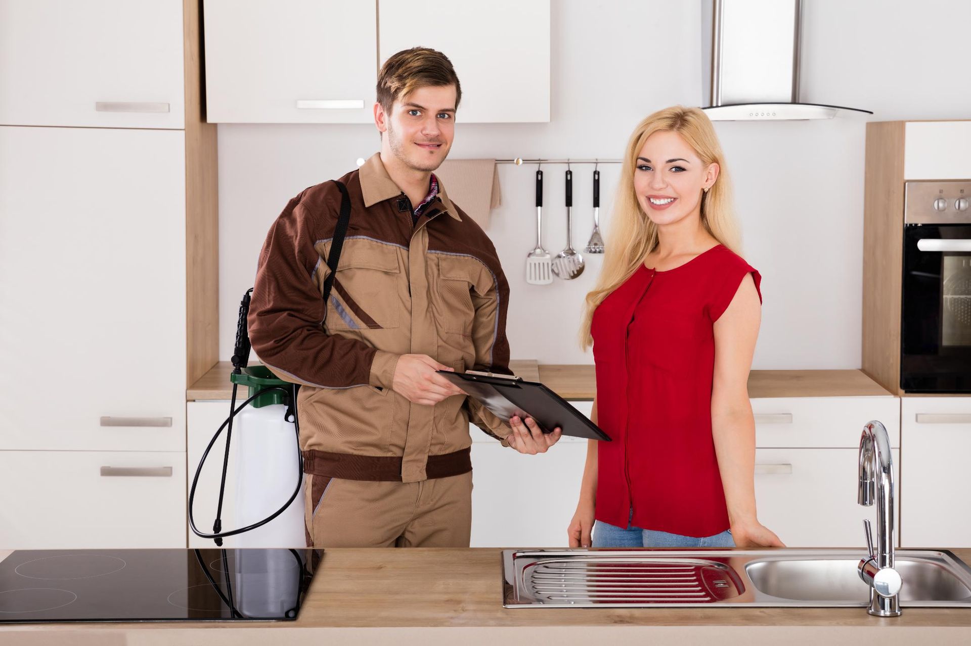 A man is standing next to a woman in a kitchen holding a clipboard.
