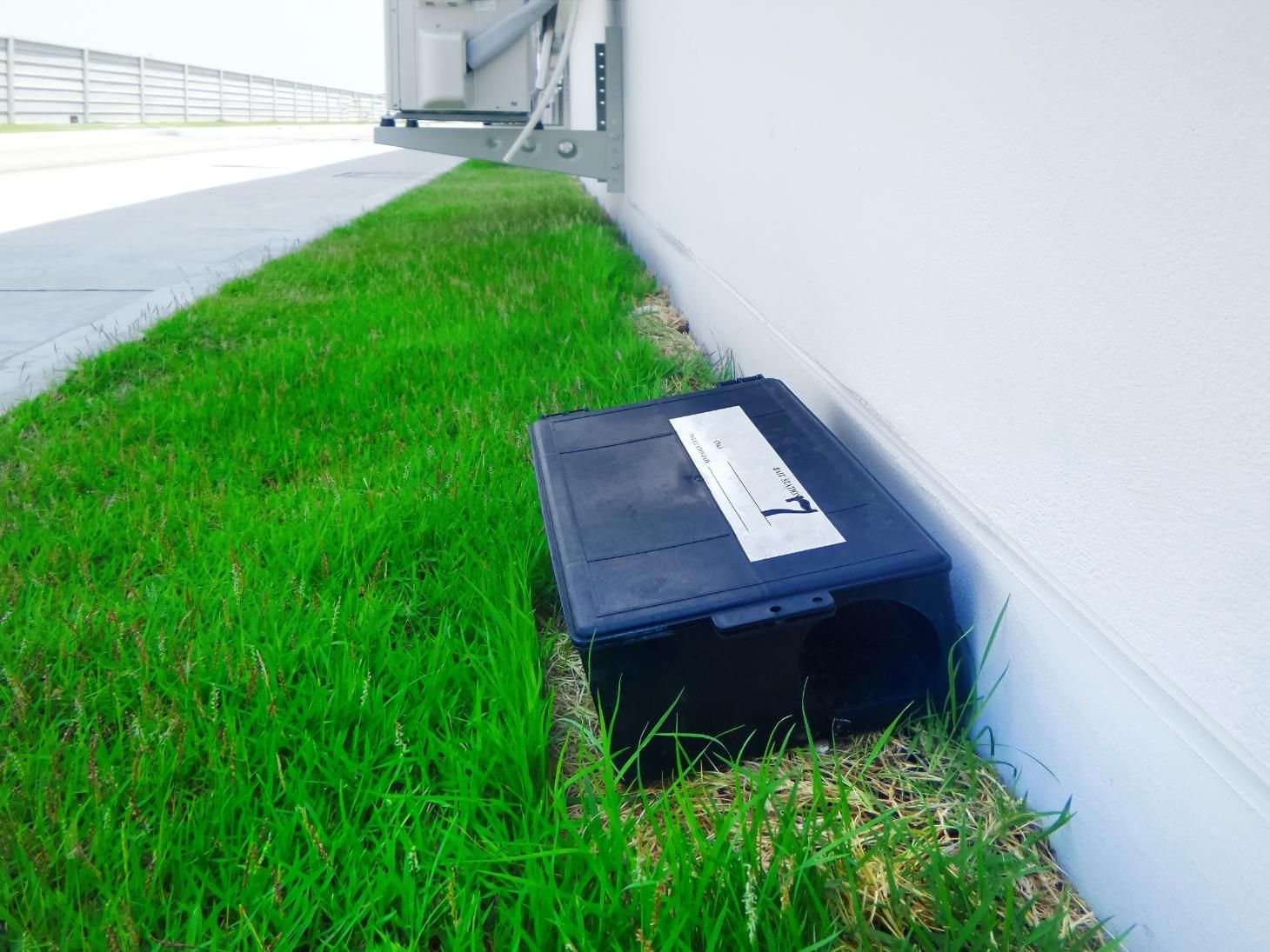 A black box is sitting in the grass next to a building.