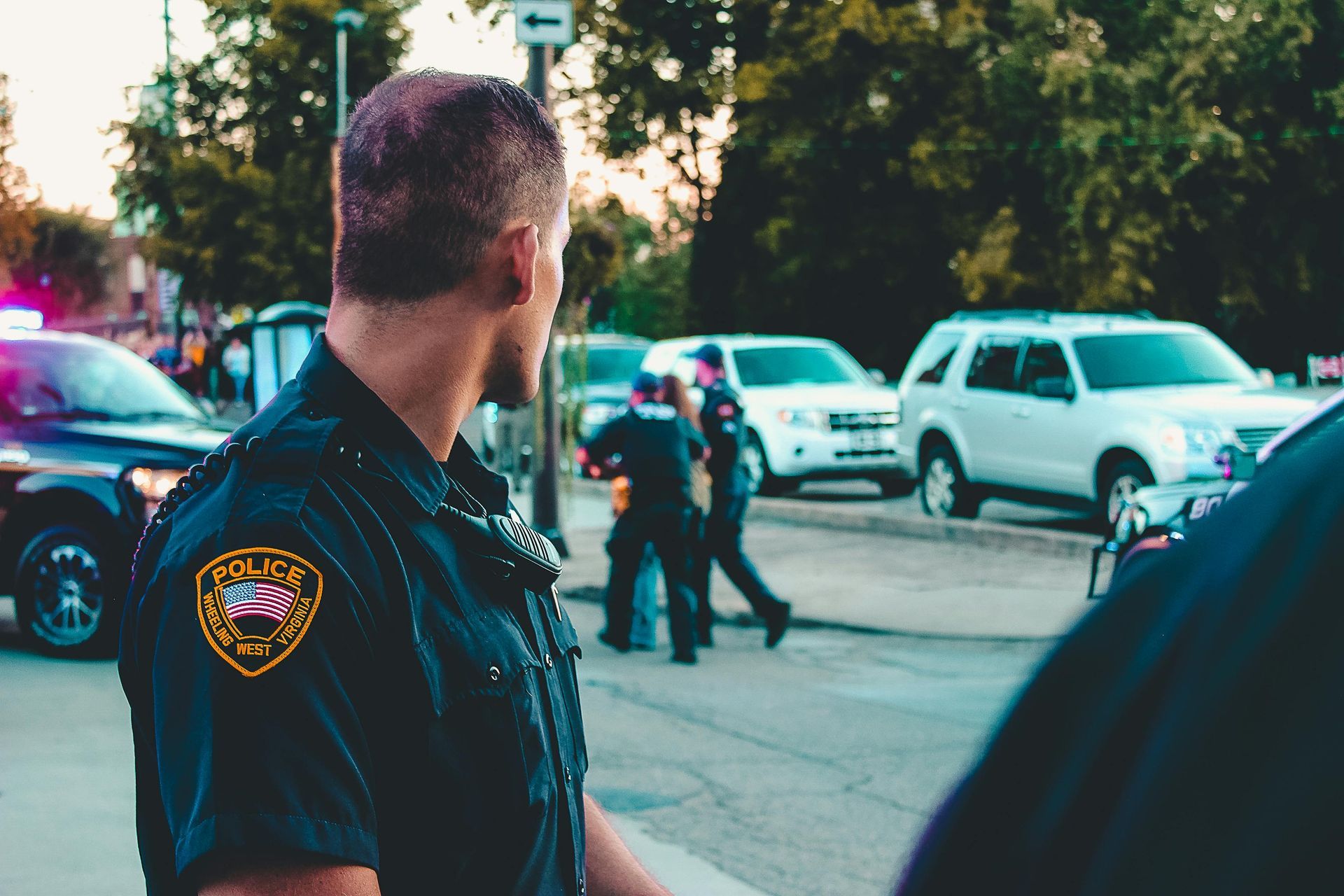 A police officer looking back over his shoulder at parked vehicles