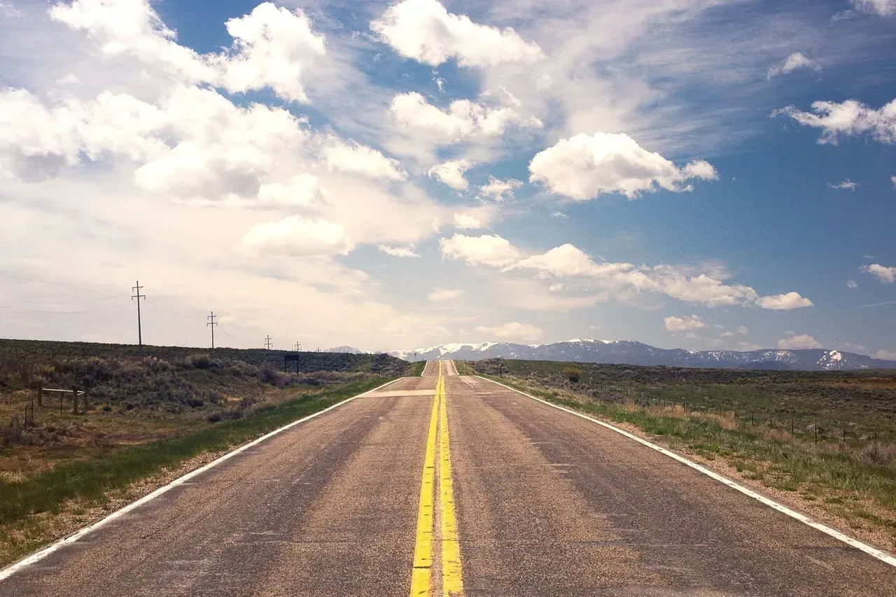 An empty road with a blue sky and white clouds