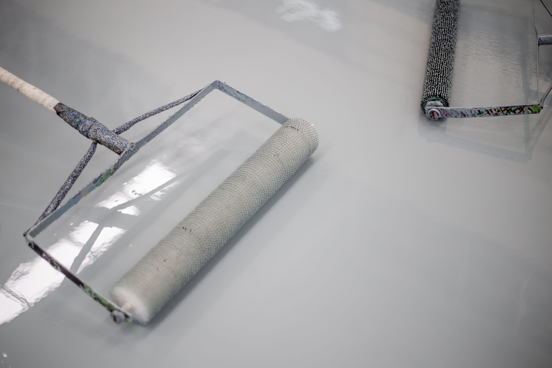 a roller is being used to paint a concrete floor .