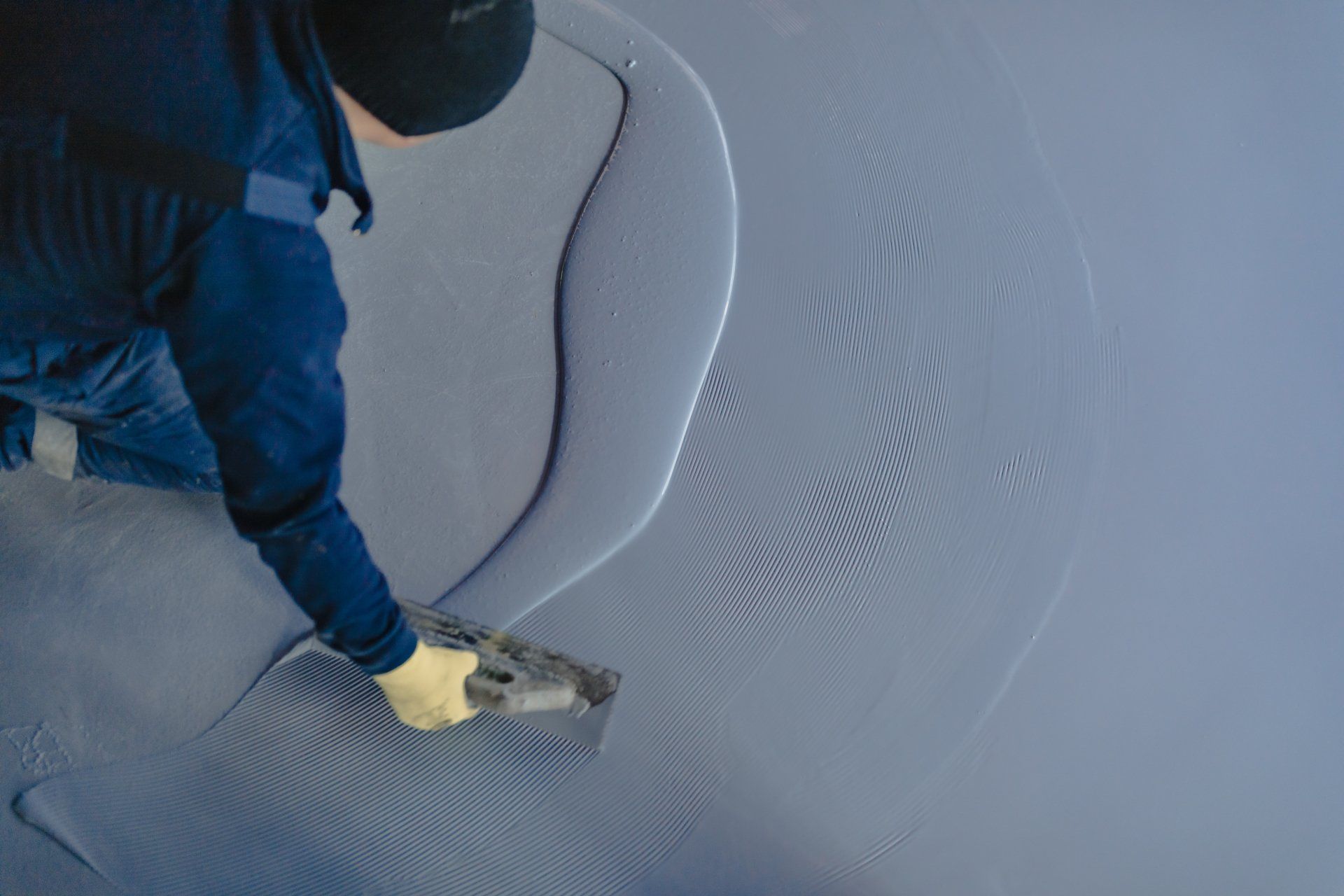 The worker applies gray epoxy resin to the new floor