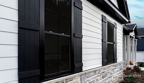 Modern house exterior featuring white horizontal siding, black window shutters, and a stone base.