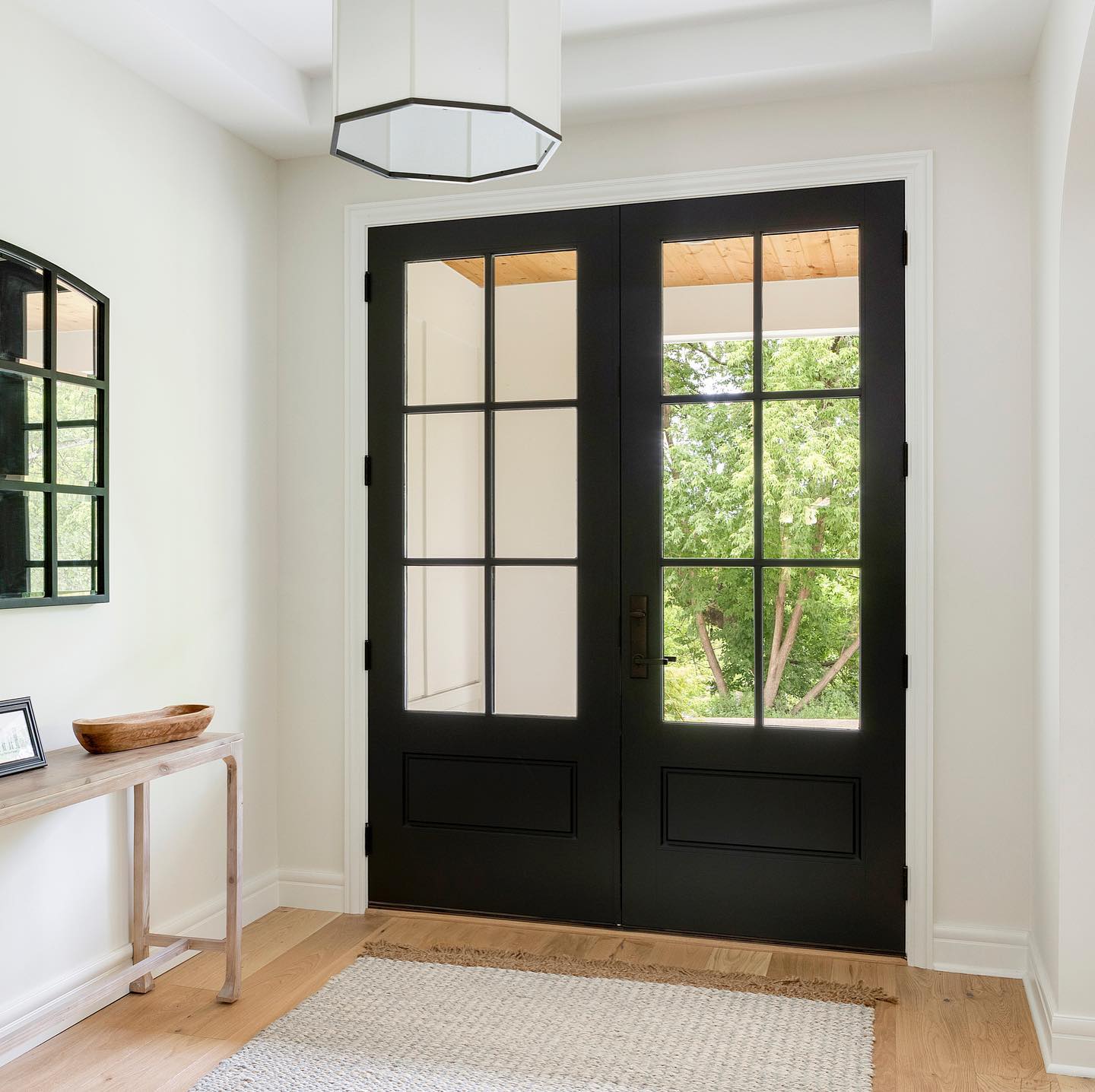 A hallway with a black door and a mirror on the wall
