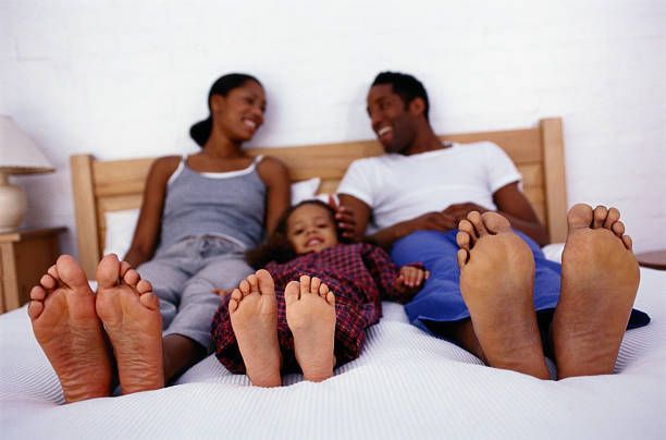 Happy Family Sitting on a Bed — Quality Shoe Shop in Maroochydore, QLD
