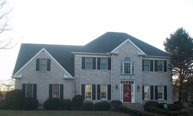 A Large Brick House with Black Shutters and A Red Door