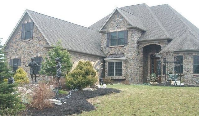 A Large Brick House with A Statue of A Man Riding a Horse in Front of It.