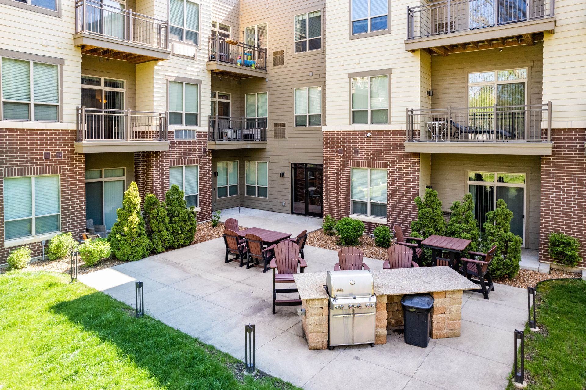 a patio area with tables and chairs and a grill