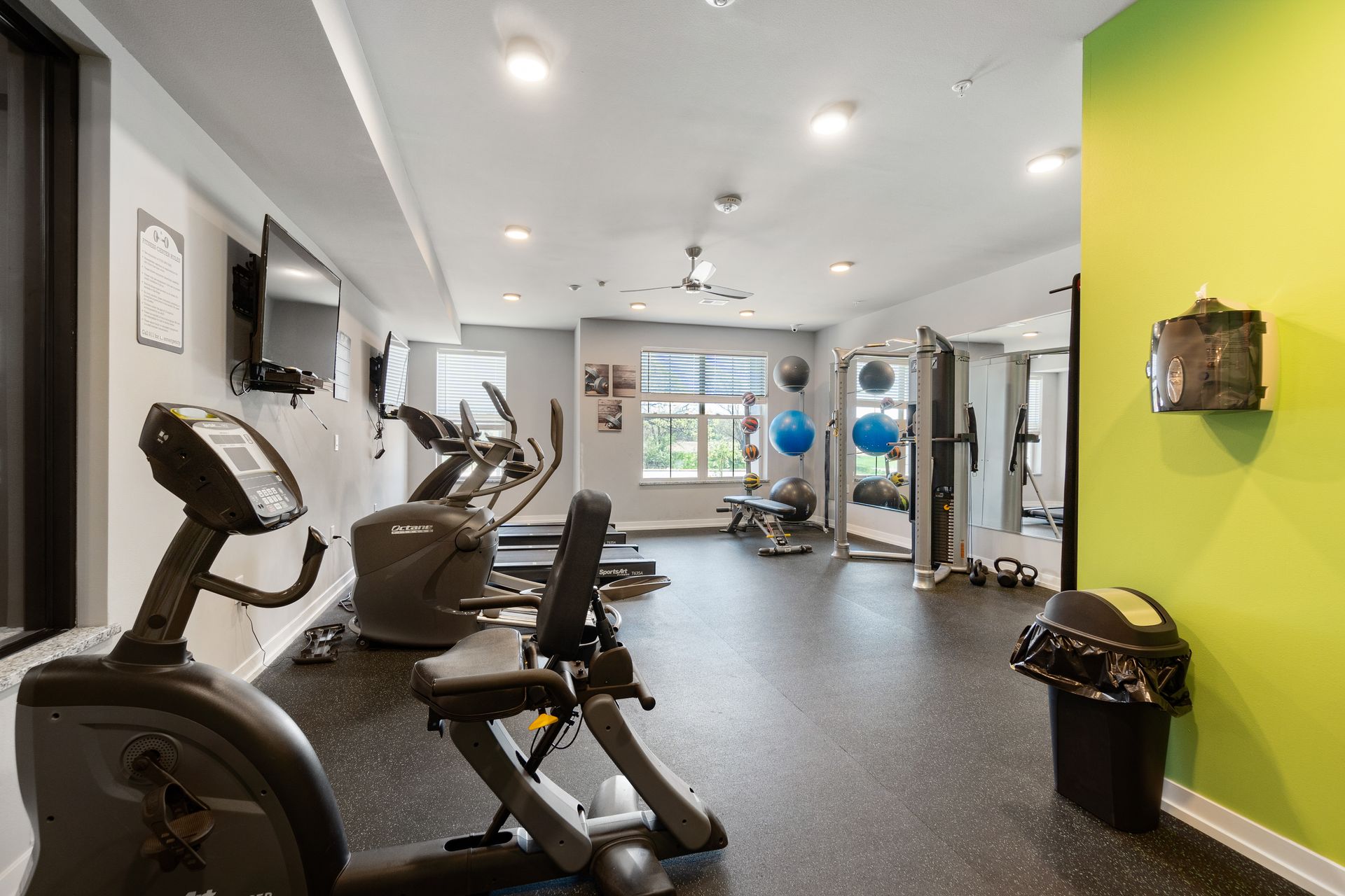 a gym with exercise bikes and treadmills and a green wall