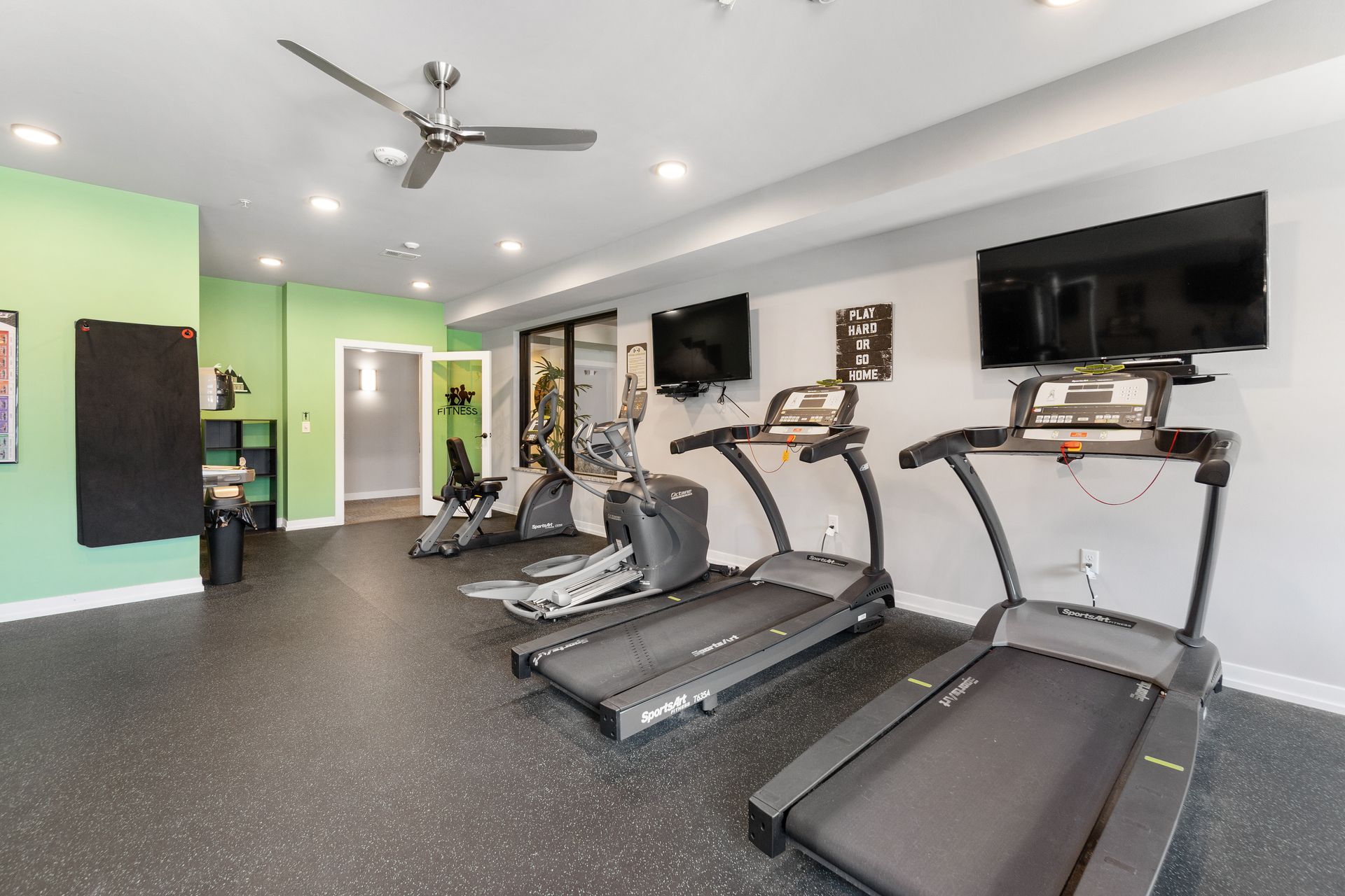 treadmills in a gym with a sign on the wall that says play hard or go home