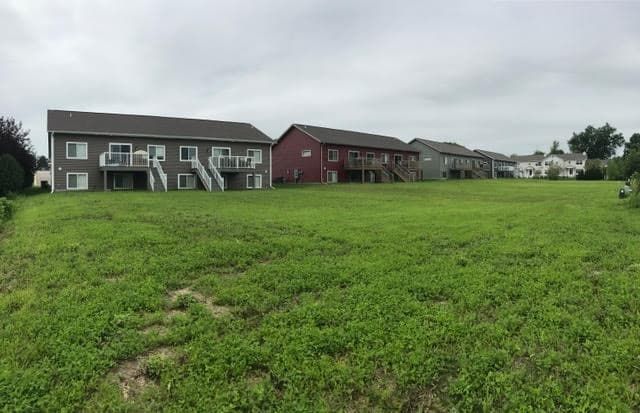 there is a large grassy field in front of a row of houses .