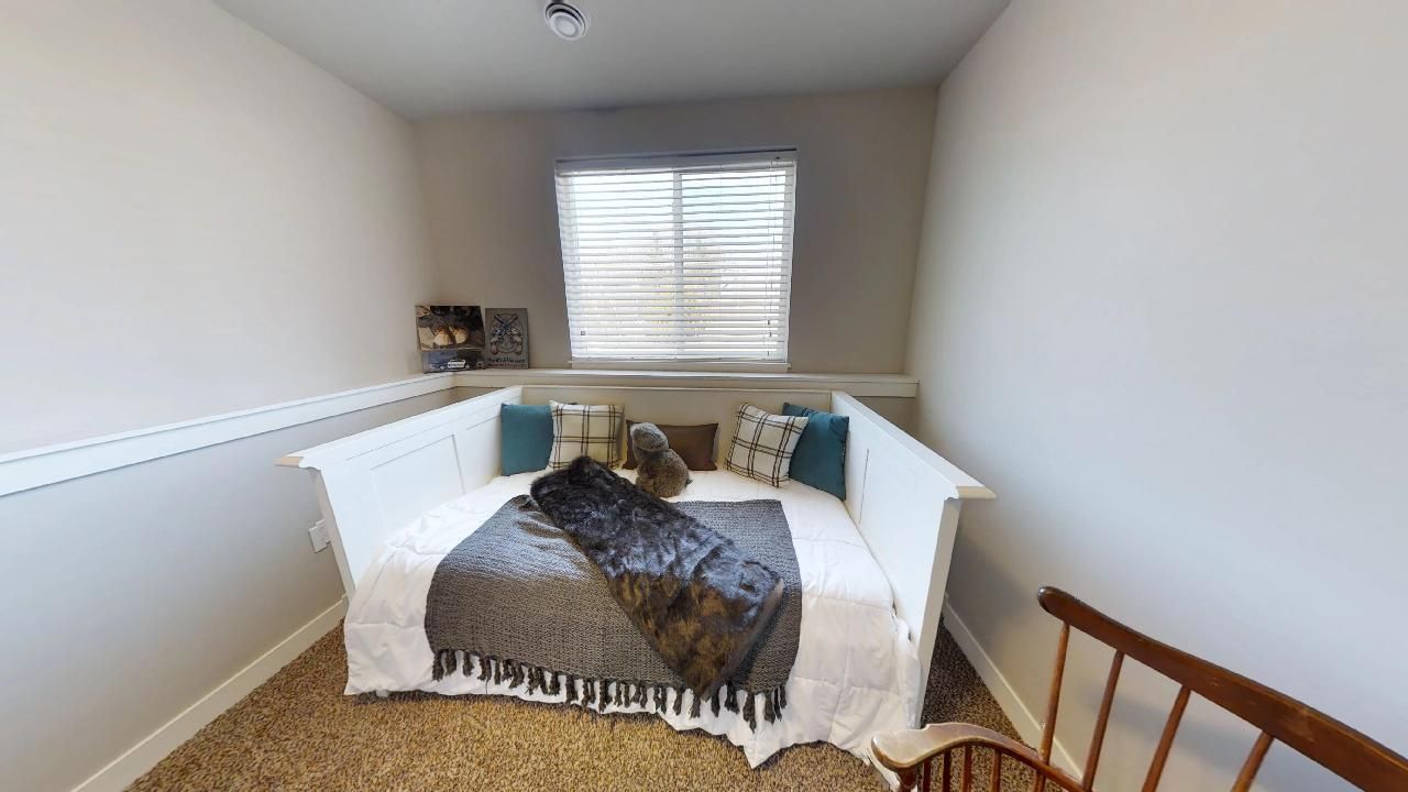 a bed with a blanket and pillows in a small room