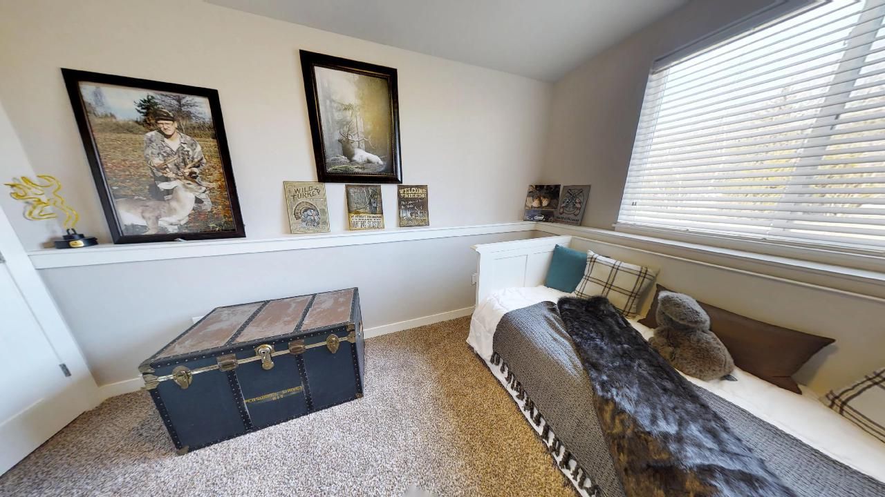 a bedroom with a bed a trunk and pictures on the wall