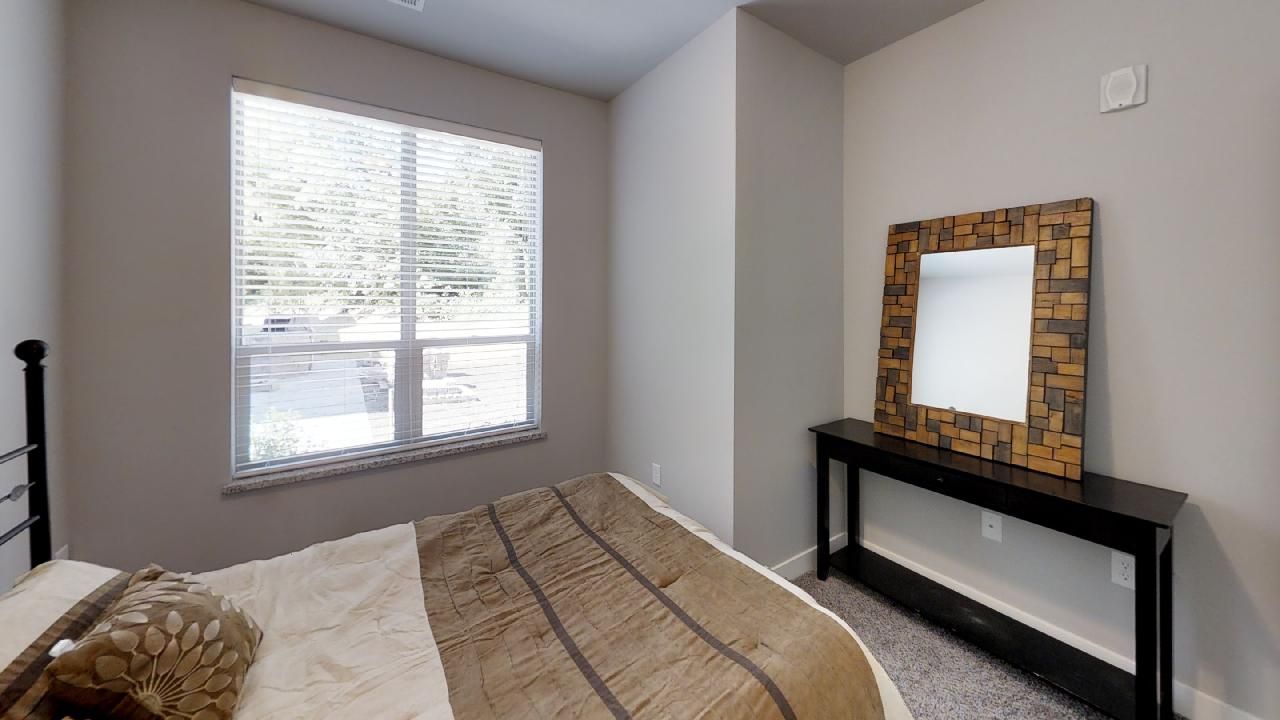 a bedroom with a bed a mirror and a window