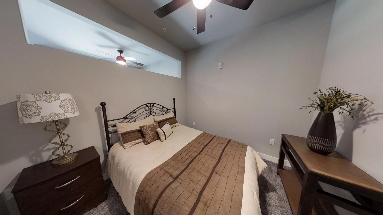 a bedroom with a bed a lamp and a ceiling fan