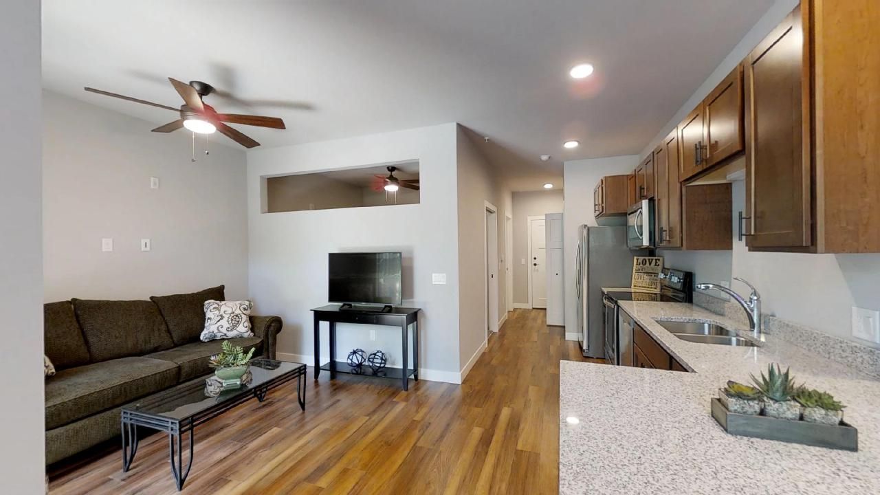 a living room with a ceiling fan and a flat screen tv