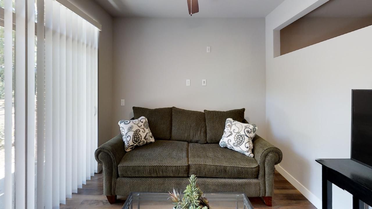 a living room with a green couch and white pillows