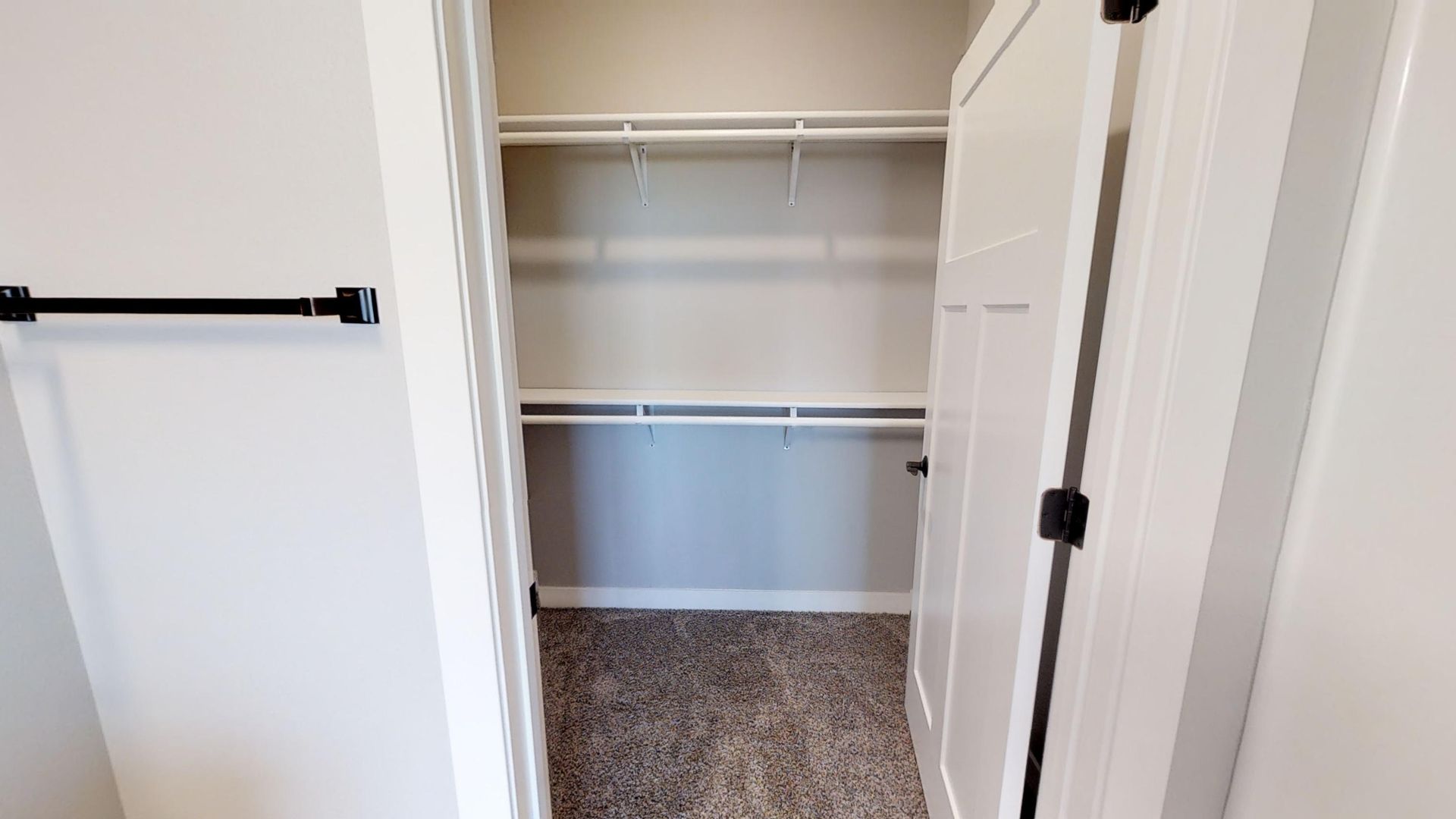 a walk in closet with a carpeted floor and white shelves