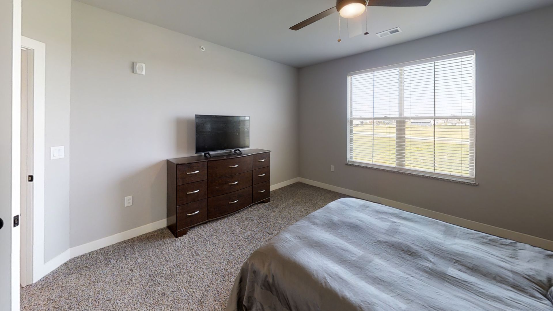 a bedroom with a bed a dresser and a flat screen tv