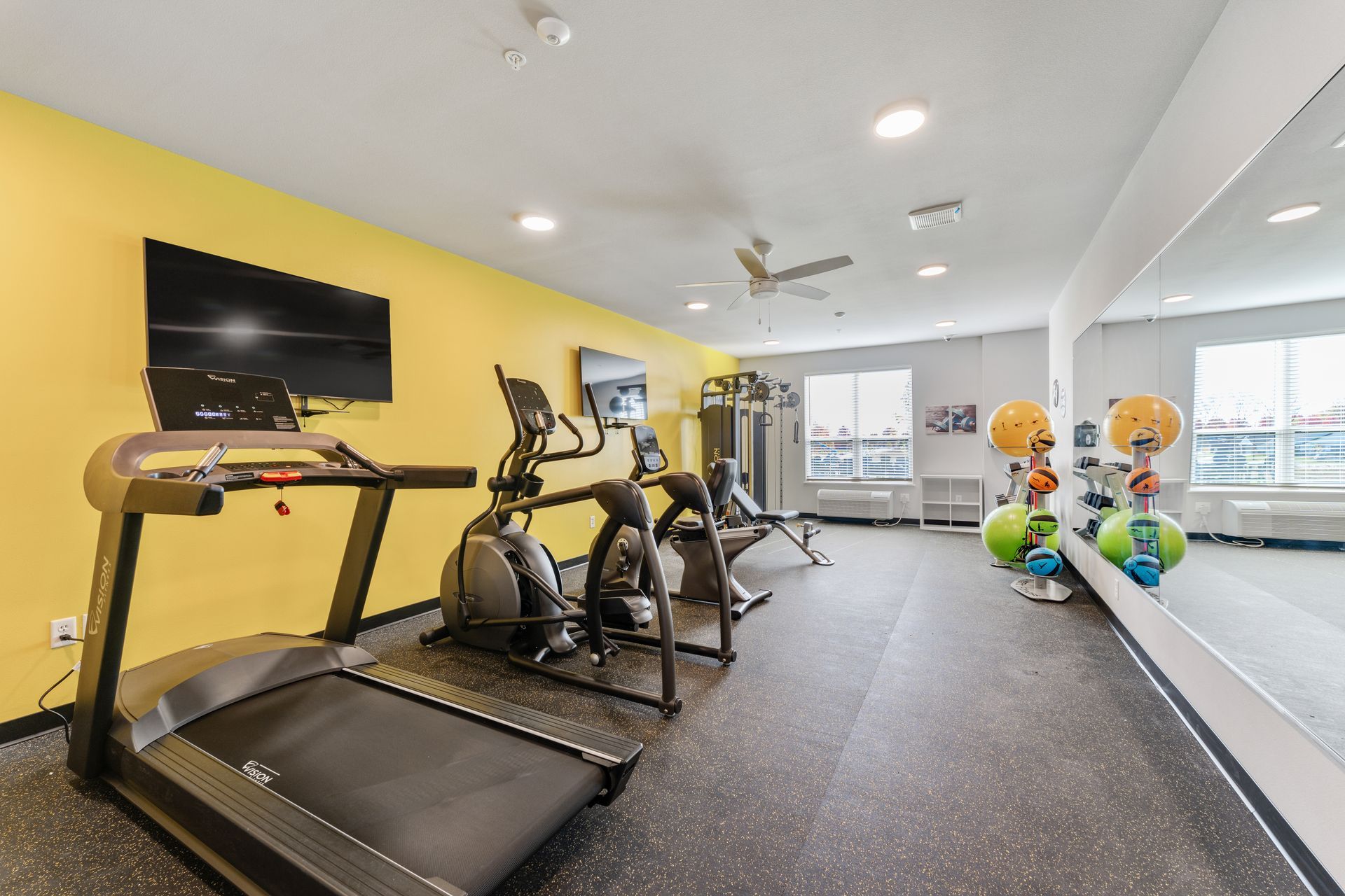 a gym with treadmills ellipticals and a flat screen tv