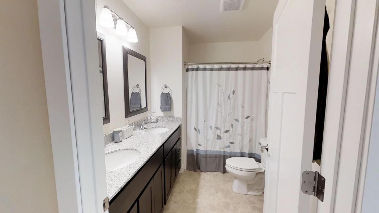 a bathroom with two sinks a toilet and a shower curtain