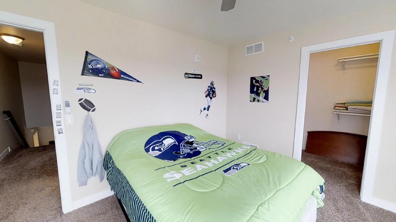 a bedroom with a bed that has a seahawks comforter on it