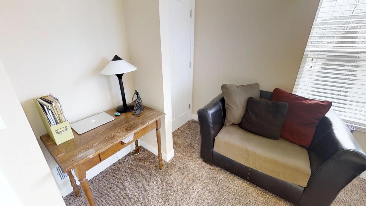 a room with a chair and a desk with an apple laptop on it