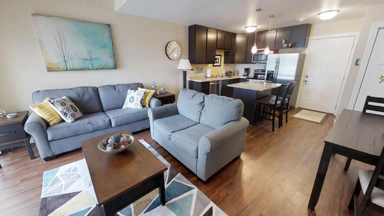a living room with a couch and chairs and a clock on the wall