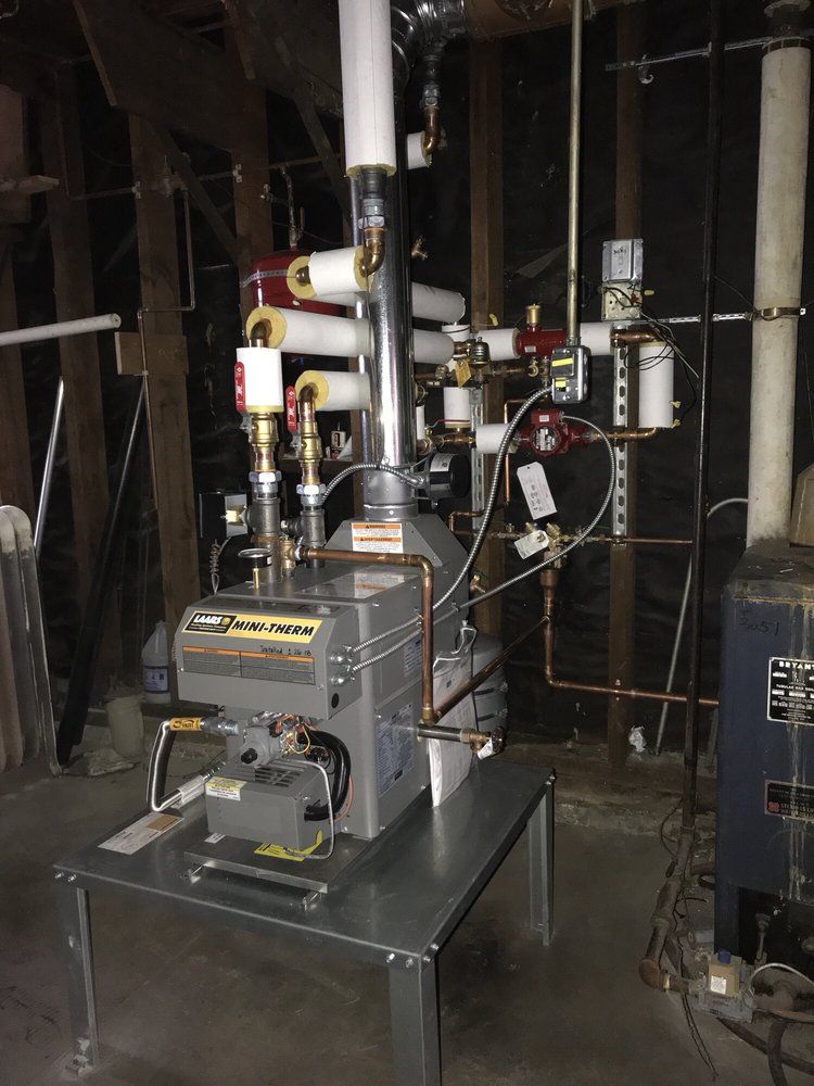 Industrial boiler or furnace equipment installed in a dim utility room with exposed insulation and pipes