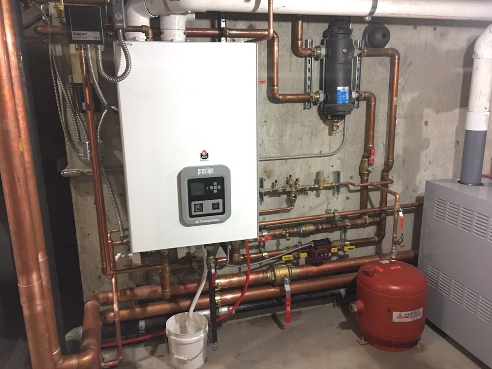 Wall-mounted boiler and red expansion tank amid exposed copper pipes in a utility room