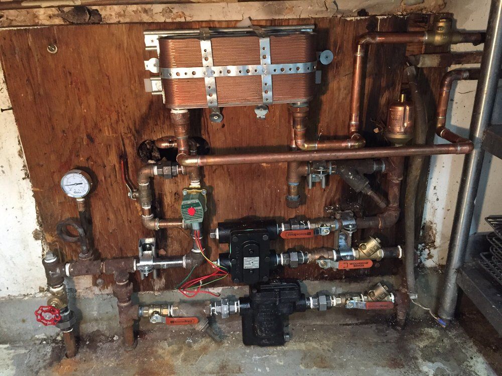 Residential plumbing manifold with pipes, gauges, valves, and brass fittings mounted on a wooden wall