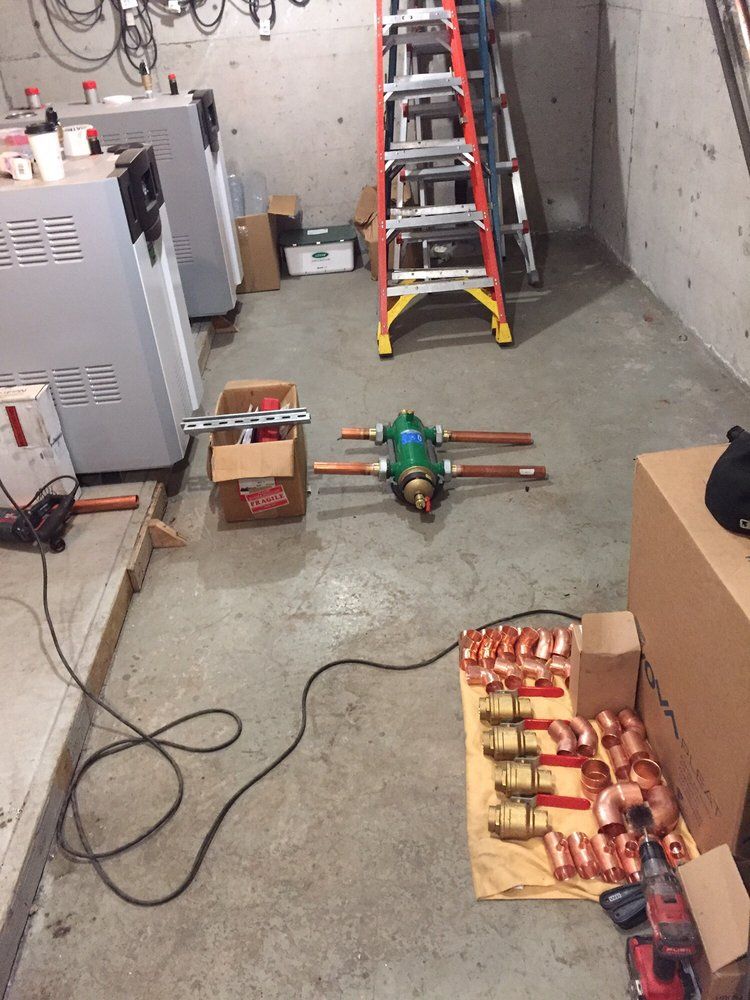 Workshop floor with tools, cables, a ladder, and metal parts laid out for repair
