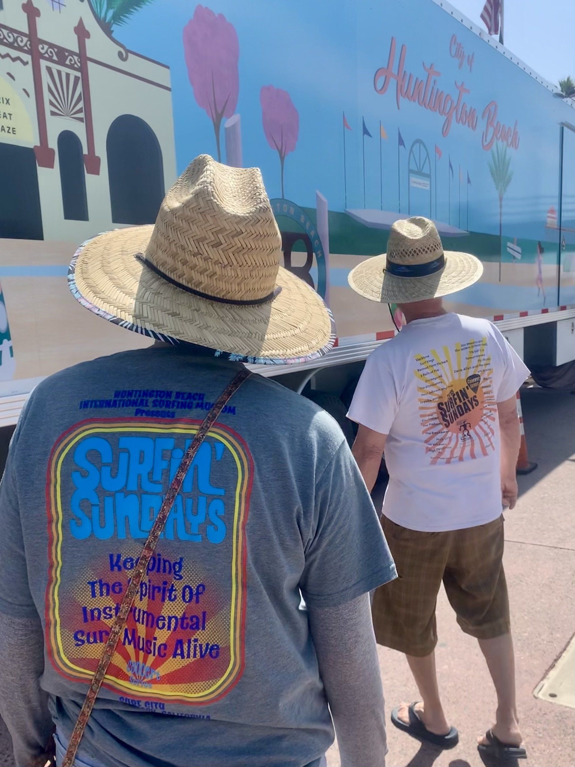 A man wearing a straw hat is standing in front of a truck.