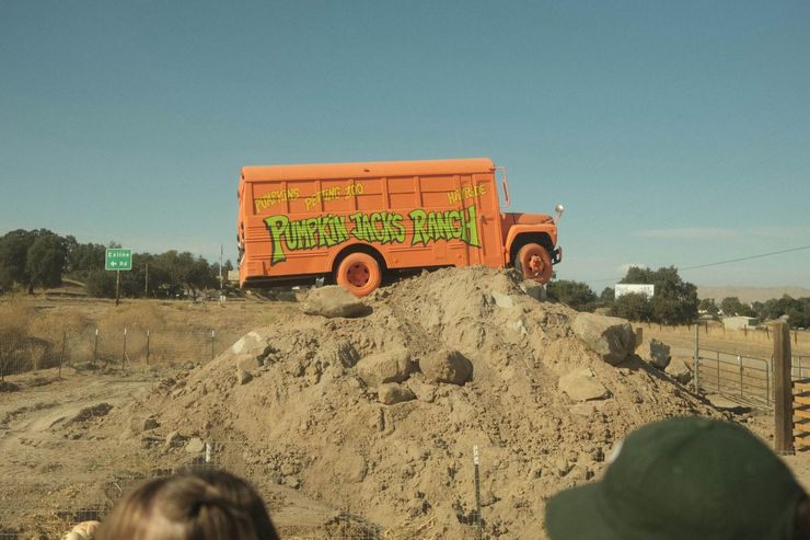 Pumpkin patch with hay bales and a smiling jack-o’-lantern under a blue sky